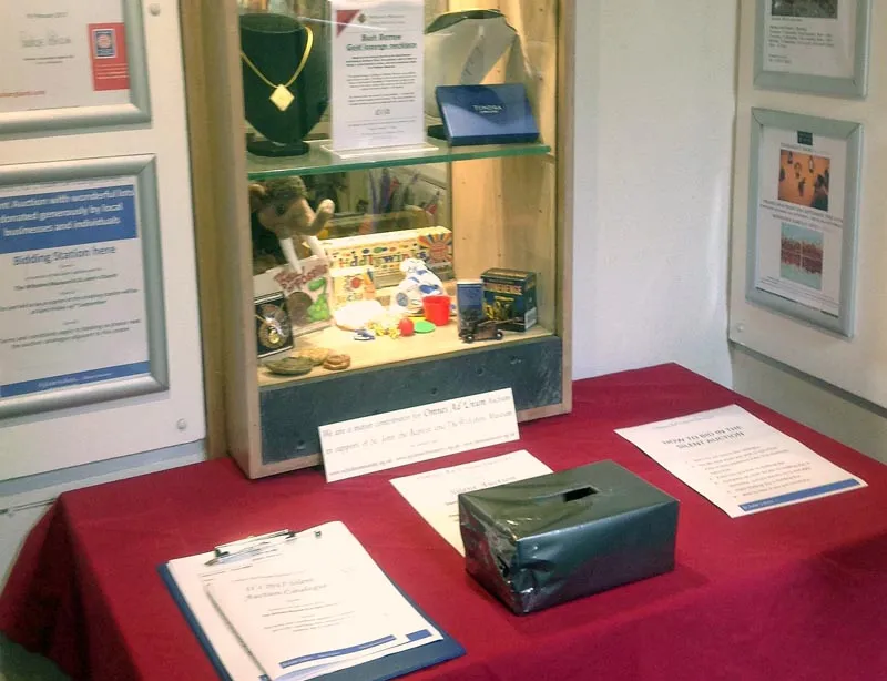 The Omnes ad Unum silent auction display in St John's, with a bidding station, catalogue and sealed-bid box